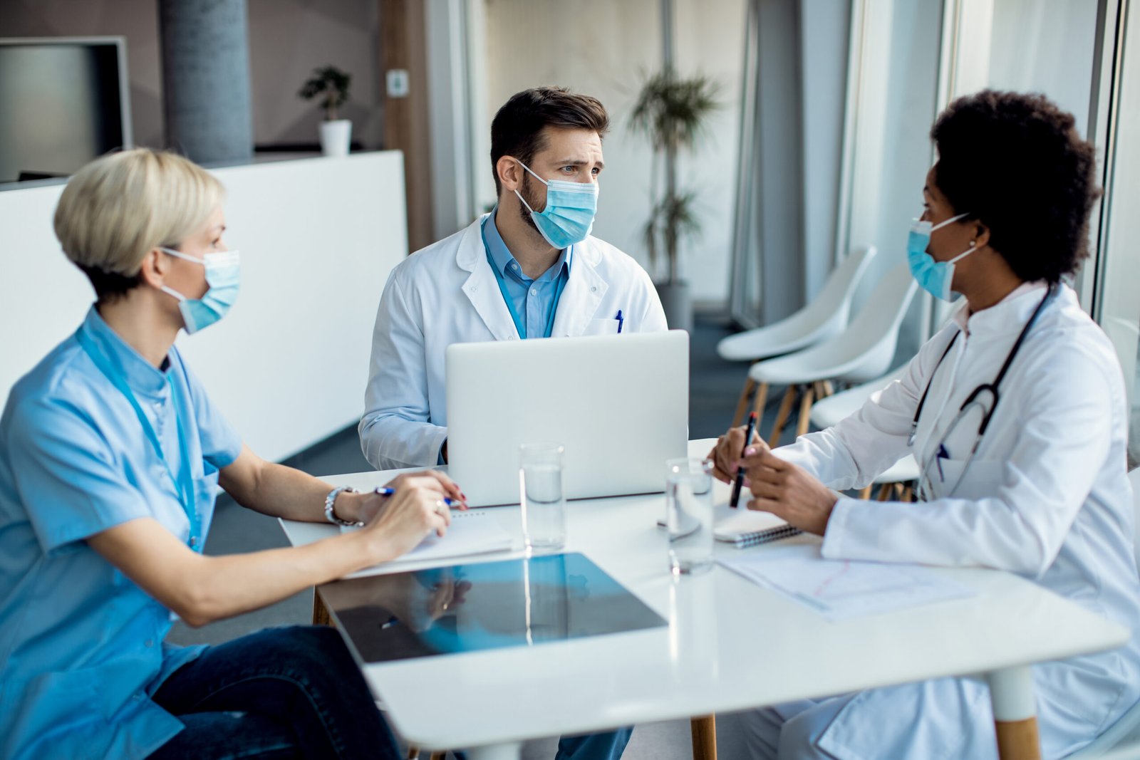 Group of healthcare experts with face masks talking during a mee